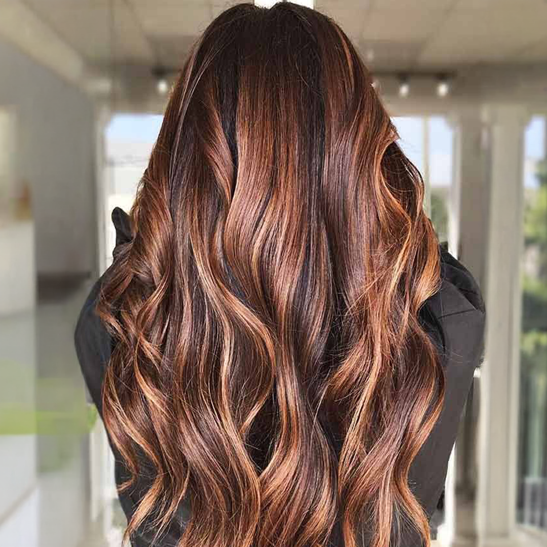 Chestnut brunette hair with subtle highlights, soft waves, trendy fall 2025 hairstyle, warm rich tones with natural dimension.
