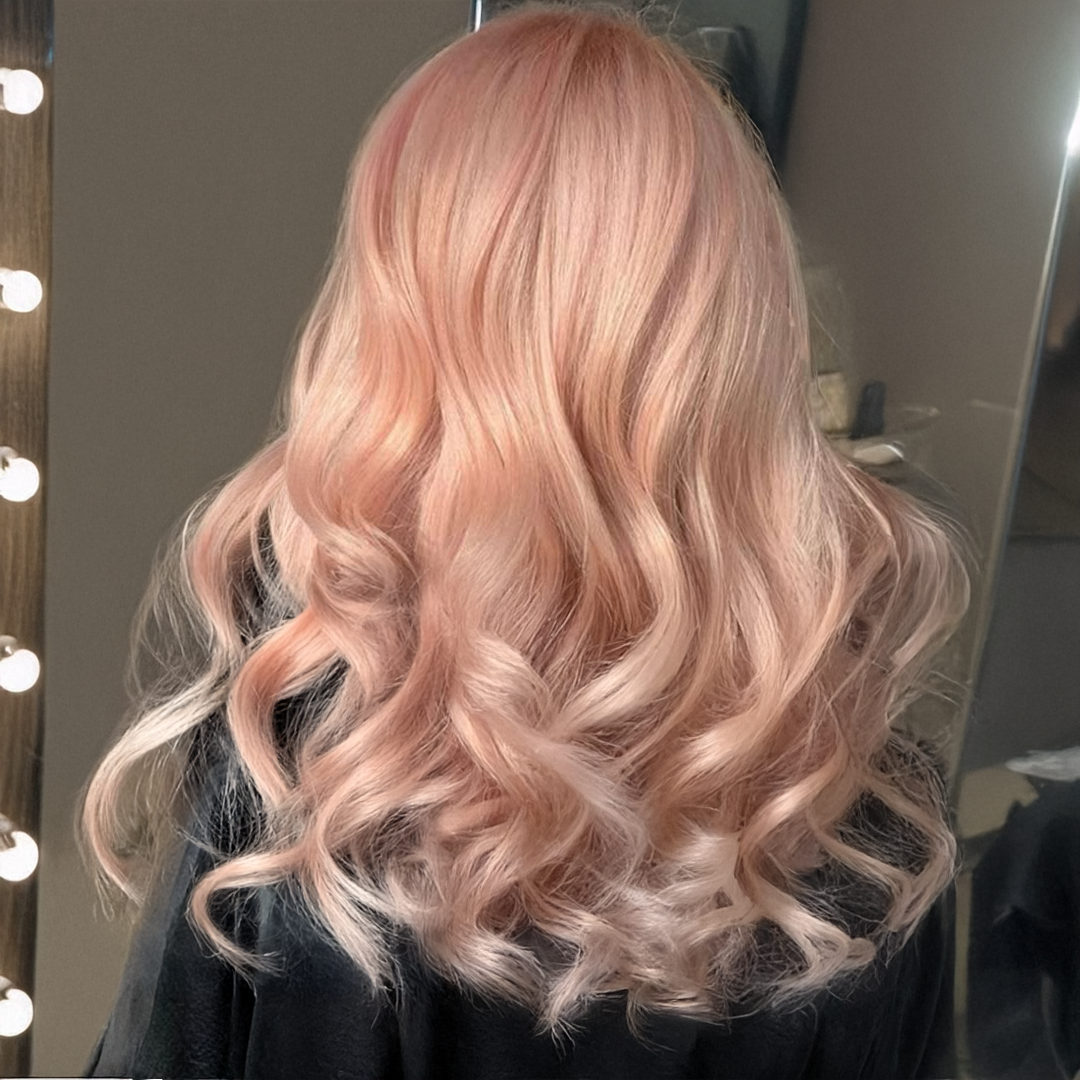 Soft peachy rose hair colour styled in loose waves, capturing a gentle and romantic fall 2025 trend.